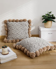 Coussin gris à pompons en matière mouton