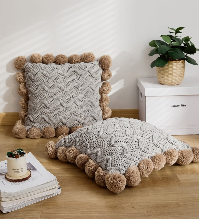 Coussin gris à pompons en matière mouton