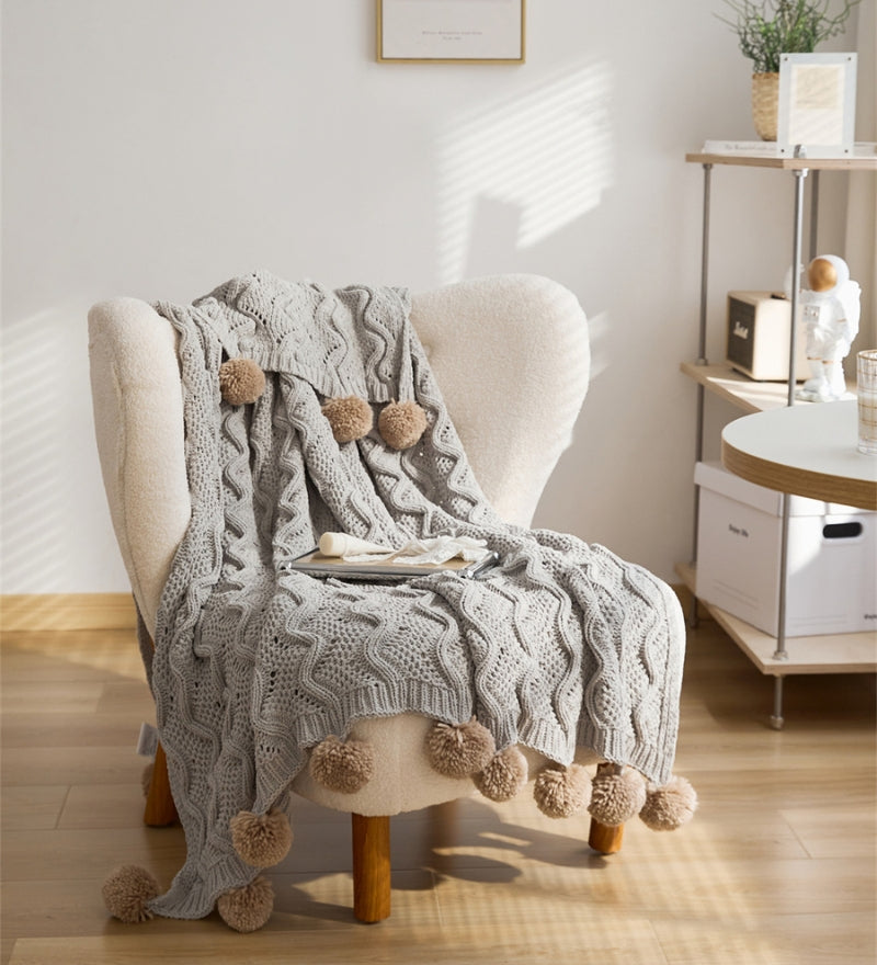Plaid de couleur gris avec pompons en fourrure